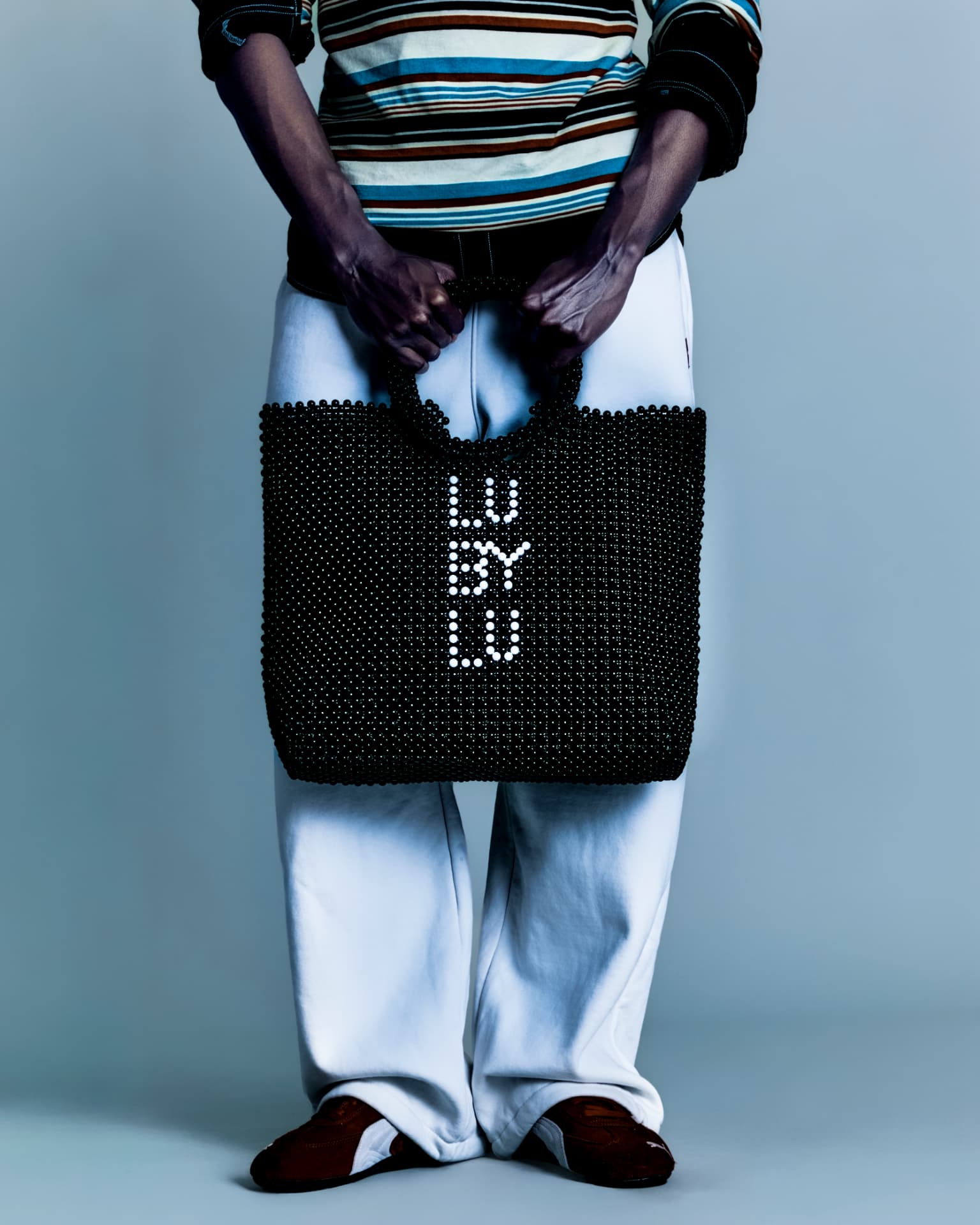 Detail of the beaded LU BY LU tote against white trousers