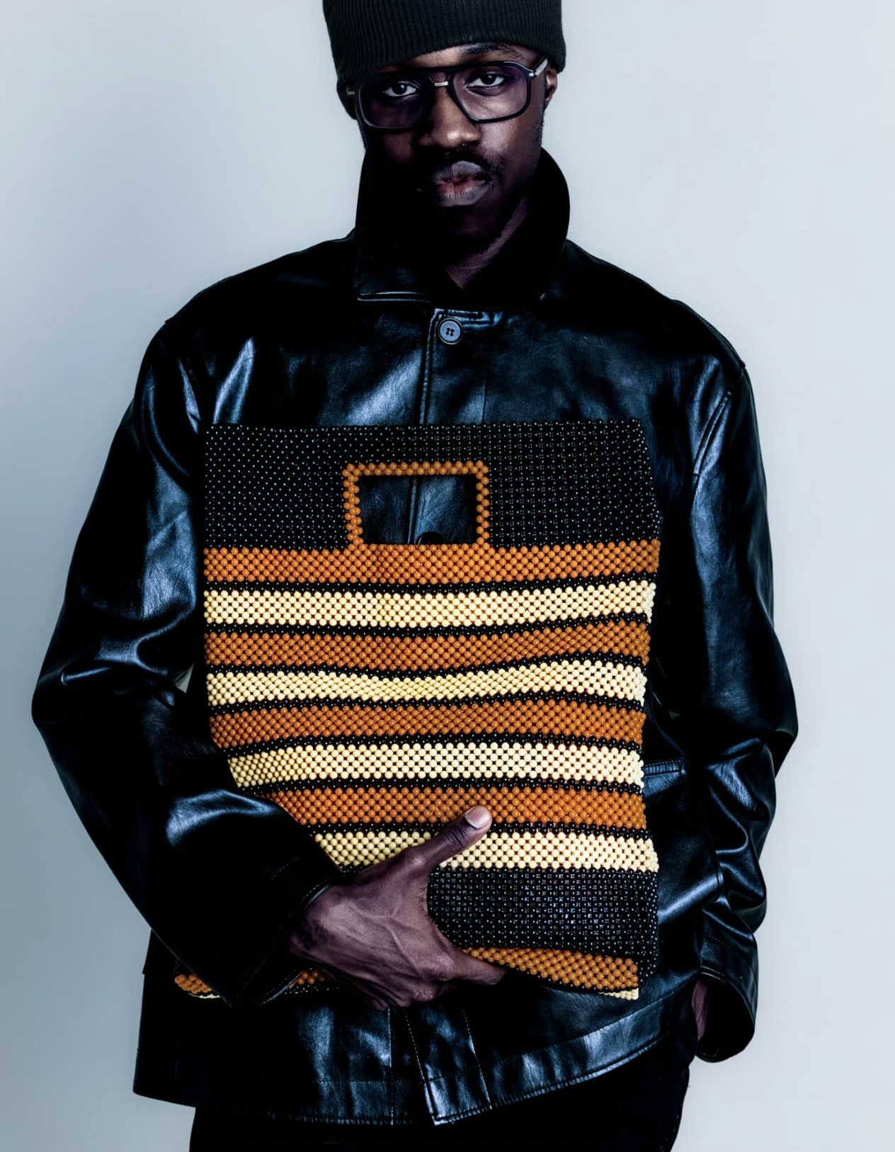 Model in a black leather jacket holding a striped beaded bag