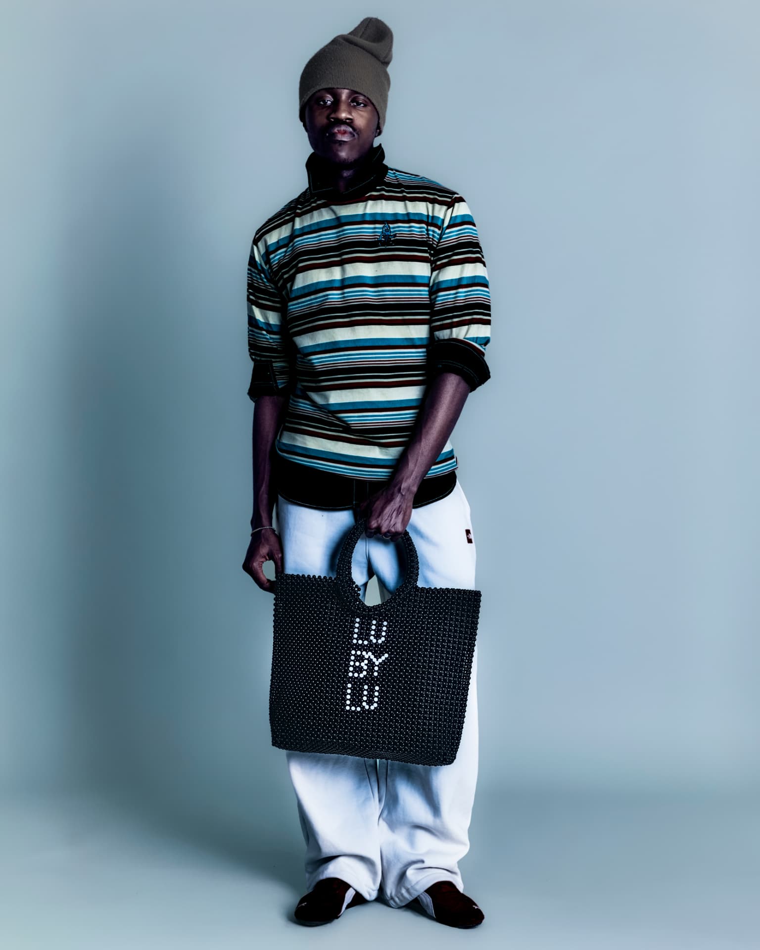 Model in striped knit holding a beaded LU BY LU tote