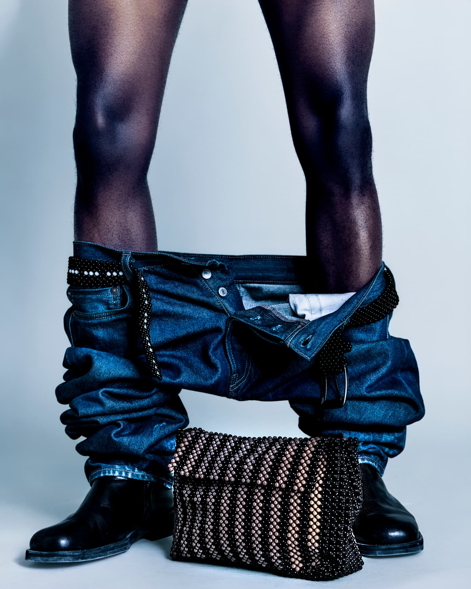 Beaded clutch photographed at floor level with denim and boots