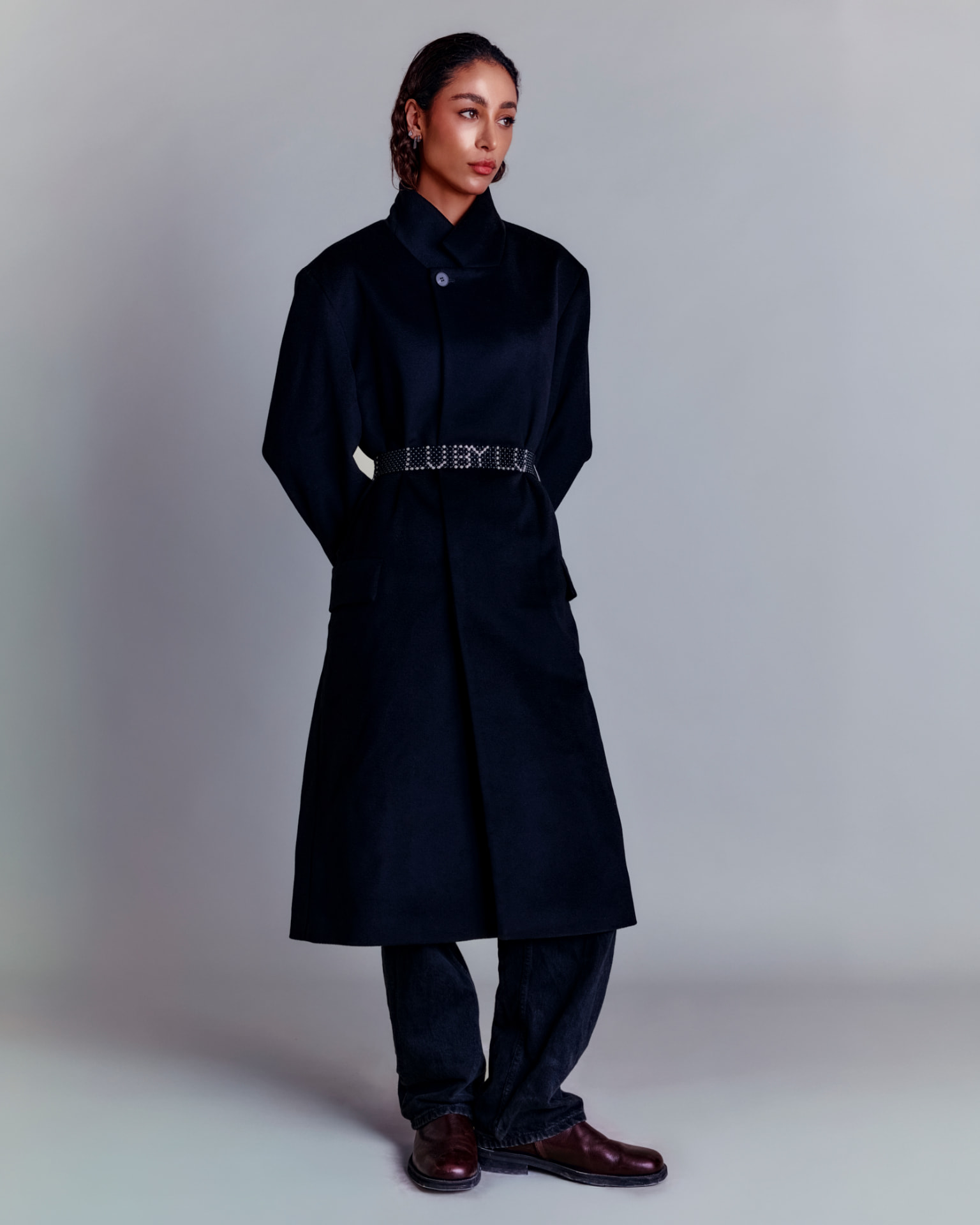 Full-length figure in a navy belted coat with a beaded LU BY LU belt